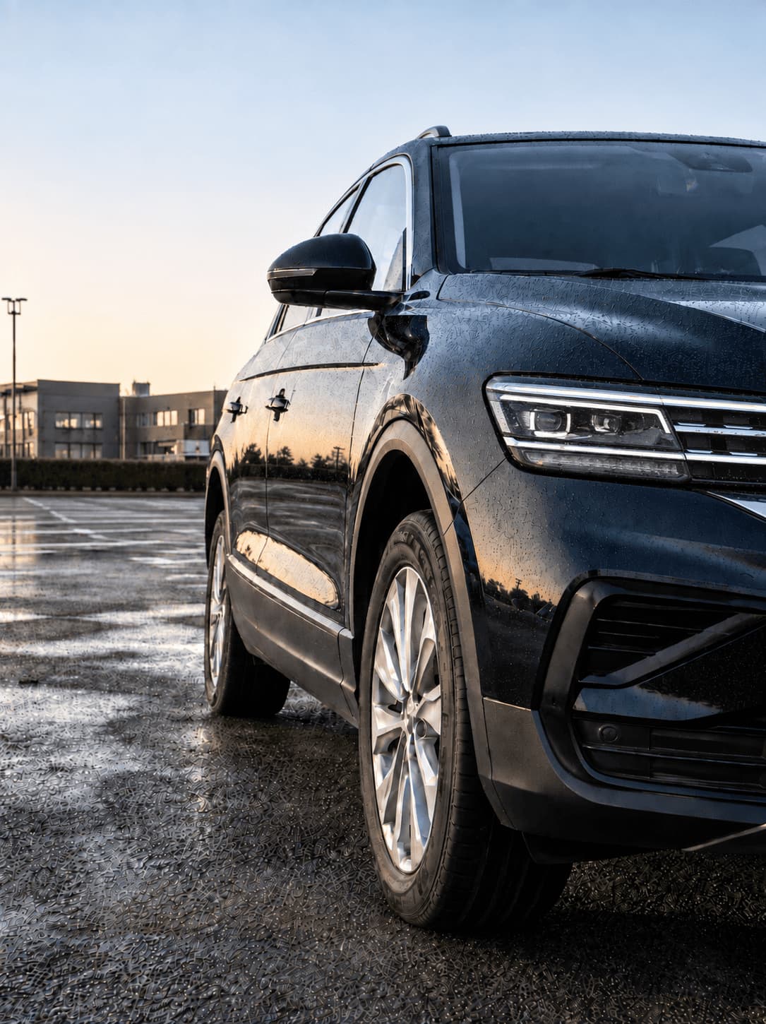 SUV sombre stationné sur un parking humide au crépuscule